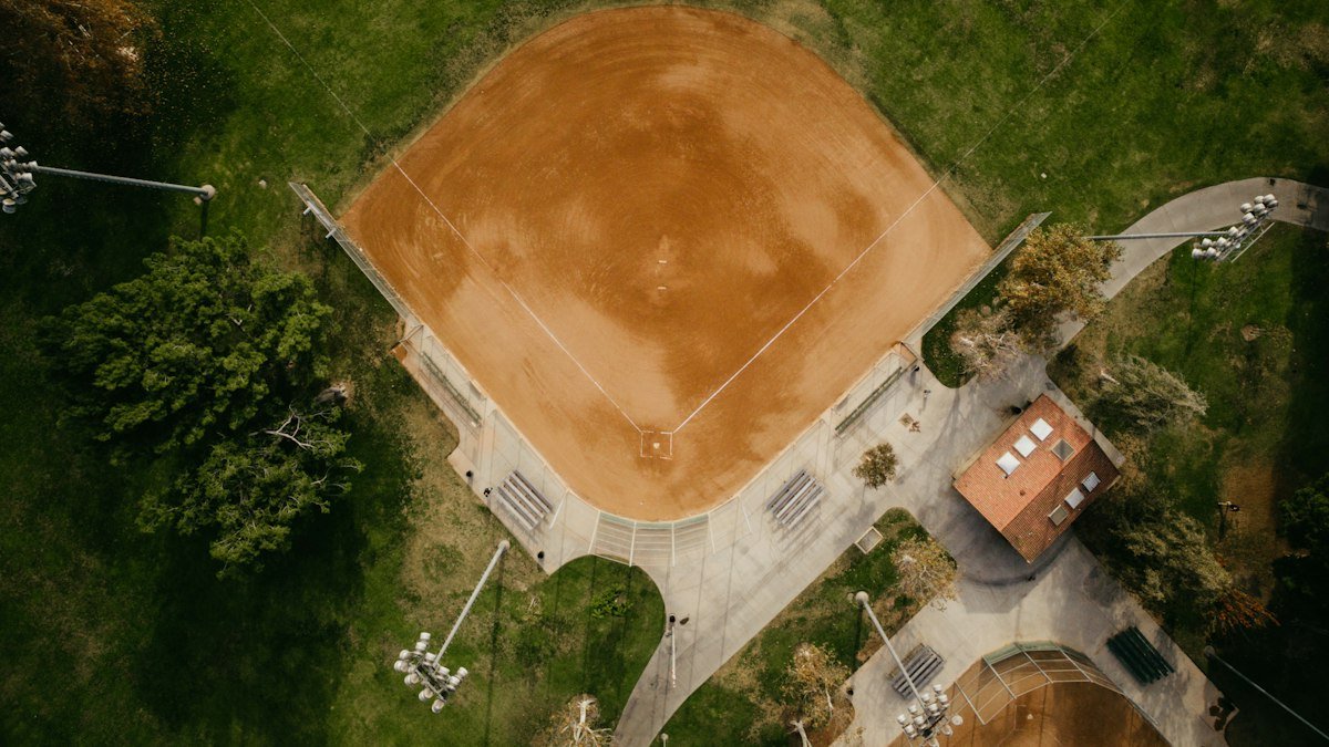 Aerial view of a baseball diamond surrounded by trees and a park path
