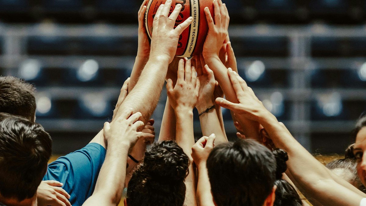 A group of basketball players reaching up together for a ball