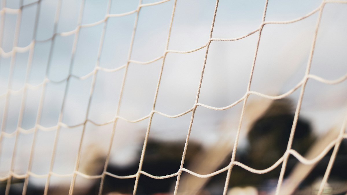 Close view of a white football goal net in soft focus