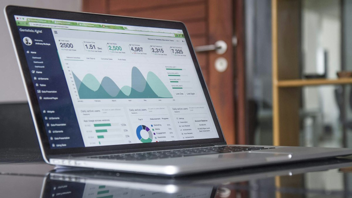 A laptop on a desk showing an analytics dashboard with line charts and key figures