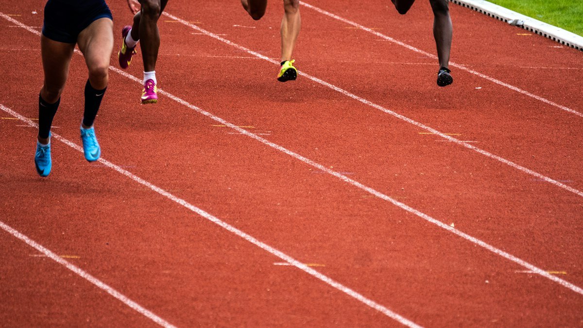 Close view of runners legs and shoes on a red running track