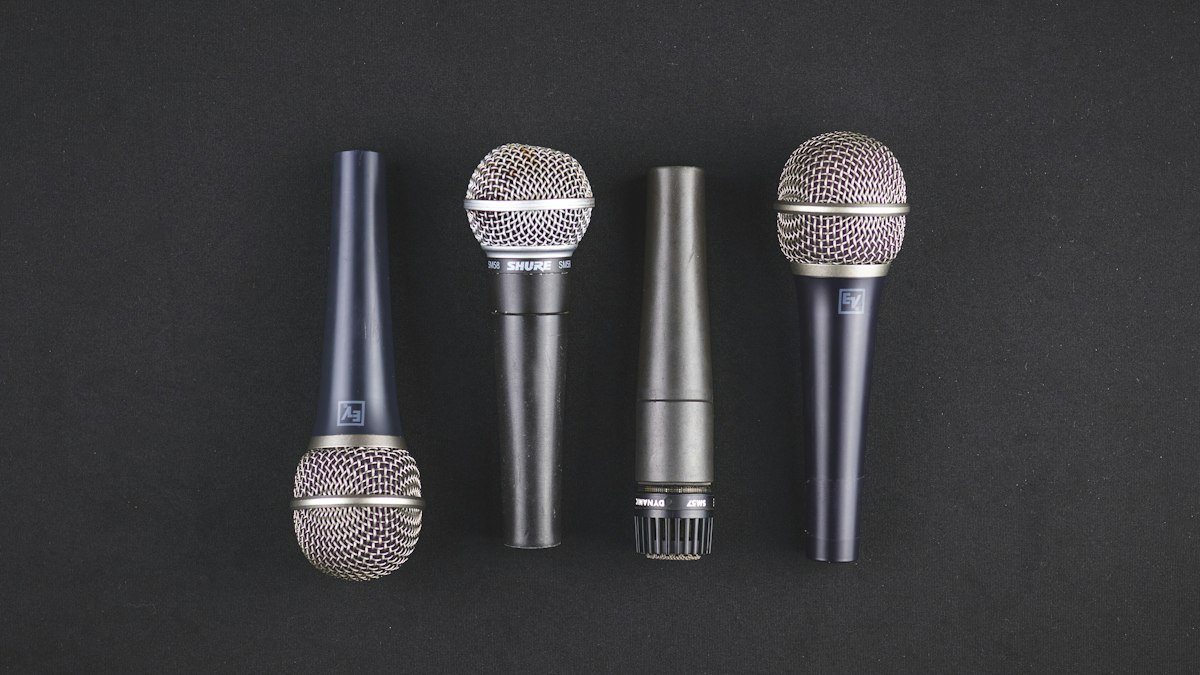 Four microphones lined up side by side on a dark surface