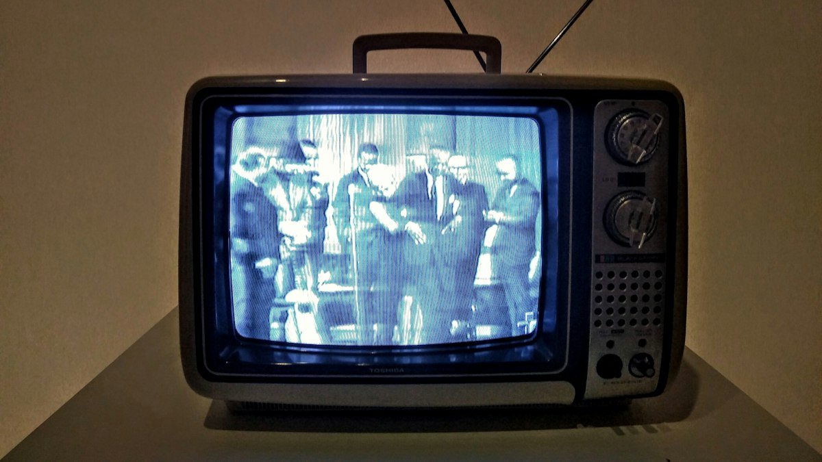 A vintage portable television set glowing with a black-and-white broadcast, representing sports coverage from an earlier era